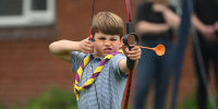 Prince Louis of Wales tries his hand at archery while taking part in the Big Help Out, during a visit to the 3rd Upton Scouts Hut in Slough, west of London on May 8, 2023, where the family joined volunteers helping to renovate and improve the building. 