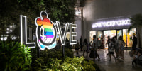 Image: Visitors walk past a LOVE sign with a Mickey Mouse symbol painted in the LGBTQ+ Pride flag colors at the Disney Springs complex in Walt Disney World on July 6, 2022, in Lake Buena Vista, Fla.