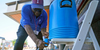 A guard pours water to stay hydrated while working security outside in Arlington, Texas, Monday, June 26, 2023. 