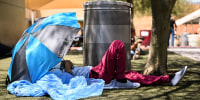 Image: A Phoenix resident rests under shade while seeking protection from the sun and heat at the Human Services Campus during a record heat wave in Phoenix on July 18, 2023.