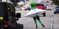A person in an alien costume roller skates through traffic in Roswell, N.M.