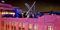 Workers install lighting on an "X" sign atop the company headquarters, formerly known as Twitter, in downtown San Francisco, on July 28, 2023.