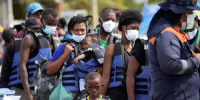 Migrants from Haiti board a boat to navigate to the border with Panama in Necocli, Colombia, on September 24, 2021. - Thousands of migrants remain stranded in a Colombian port town as they wait for boats to cross into neighboring Panama on their way to the United States, a state relief agency said.