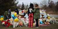People stand at a memorial outside of Oxford High School in Oxford, Mich