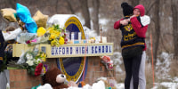 Students hug at a memorial on Dec. 1, 2021, following a shooting at Oxford High School in Oxford, Mich.
