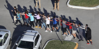 People are brought out of the Marjory Stoneman Douglas High School after a shooting n Parkland, Fla.,