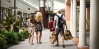 Shoppers carry bags after purchasing items from stores at the Orlando Vineland Premium Outlets mall on July 9, 2023, in Orlando, Fla.