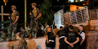 Lebanese soldiers stand guard next to an overturned truck in the Christian town of Kahaleh on Aug. 9, 2023.