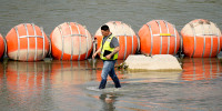 A worker inspects buoys being used as a barrier along the Rio Grande, Monday, Aug. 21, 2023, in Eagle Pass, Texas.