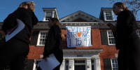 Students walk past a fraternity house with a banner memorializing three University of Virginia football players killed during an overnight shooting at the university on November 14, 2022 in Charlottesville, Va. 