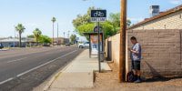 Image: Adrian Mata stands in the shade while waiting for the bus in Phoenix on July 15.