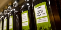 Rows of Tesco brand olive oil on a supermarket shelf in England.