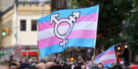 A person holds a transgender pride flag.