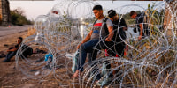 A barefoot man carefully weaves through razor wire in Eagle Pass, Texas on Sept. 23, 2023.  