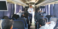 Migrant children and teenagers sit on a charter bus as a member of the Guatemalan Institute of Migration speaks