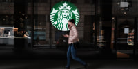 A woman walks by a Starbucks coffee shop in Manhattan, N.Y.