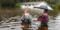 Makatla Ritchter, left, and her mother, Keiphra Line wade through flood waters in Tarpon Springs, Fla.