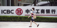 A woman walks by signage outside an Industrial and Commercial Bank of China Ltd. (ICBC) branch in Shanghai, China
