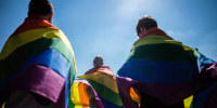Activists walk with rainbow flags around their shoulders