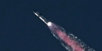 A rocket ship flies through a blue sky.