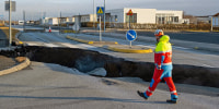 A member of the emergency services walks near a crack cutting across the main road in Grindavik, Iceland on Nov. 13, following earthquakes. 