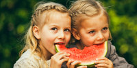 Little twin girls eating watermelon