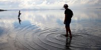 People wade in the waters of the Great Salt Lake at Antelope Island near Syracuse, Utah