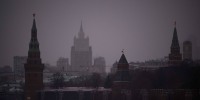 Cars slowly move along an embankment of the Moskva river past the Kremlin