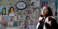 Image: A woman passes in front of photographs of missing persons 