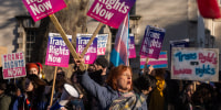 Protesters hold signs that read, "Trans Rights Now"