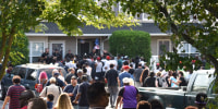 A crowd forms in front of the house of Edward Mathews, which is blocked by police.