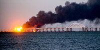 A wide angle photo of the Kerch bridge on fire and smoke billowing.