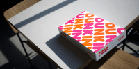A box of donuts sits on a table inside a Dunkin' location.
