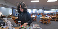 A student checks in books at Bellview Middle School in Pensacola in Florida's Escambia County on Dec. 18, 2023. 
