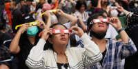 People wear protective glasses to watch a solar eclipse in Jakarta, Indonesia, on April 20, 2023.