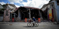 A cyclist rides past a destroyed building in Guanica, Puerto Rico