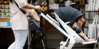 FILE PHOTO: A woman pushing her baby in a stroller shops in the Hongdae area of Seoul