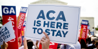 A demonstrator holds up a "ACA is Here to Stay" sign in Washington, D.C. on June 25, 2015. 