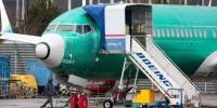A person walks past an unpainted Boeing 737-8 MAX