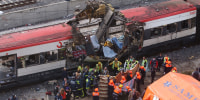 Rescue workers cover up bodies at the damaged passenger train in Madrid, Spain