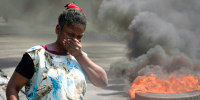 A woman walks past burning tires in Haiti 