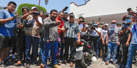 People stand around a woman who was beaten by a mob that dragged her from a police vehicle under suspicion that she had participated in the kidnapping and killing of an 8-year-old girl in Taxco, Mexico, March 28, 2024. The woman died of her injuries. 