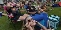People watch the total solar eclipse with glasses.