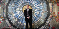 Peter Higgs stands in front of a photograph