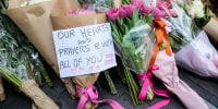 A note is left with flower tributes near a crime scene
