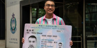 Activist Henry Tse, who won an appeal to change the gender on his ID card, poses with a mock ID card outside the immigration tower after receiving the new document in Hong Kong, Monday, April. 29, 2024.