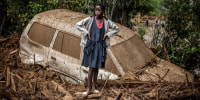 A girl looks on next to a car buried in mud after torrential rains and flash floods in the village of Kamuchiri, near Mai Mahiu, on April 29, 2024. 