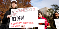 Activists hold up signs as they listen during a Title IX rally near the White House.
