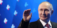 Russian President Vladimir Putin waves as he leaves a tribune after delivering a speech 