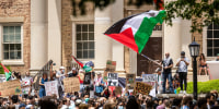 Hundreds of demonstrators hold Palestinian flags and anti-war signs on a college campus